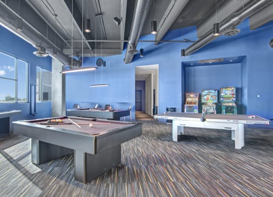 a games room with two pool tables and arcade games