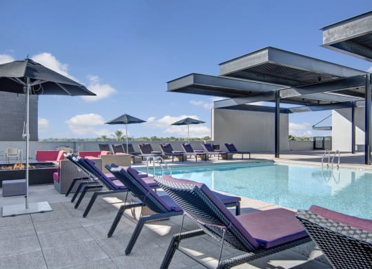a pool with lounge chairs and umbrellas on top of a building