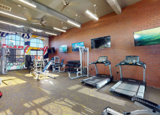 a workout room with gym equipment and a mural on the wall