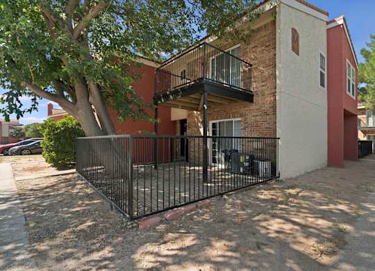 A red and white building with a black fence and a tree in front.