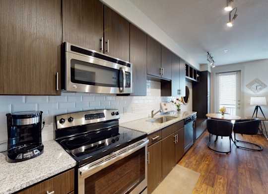 A modern kitchen with dark wood cabinets and stainless steel appliances.