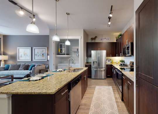 A kitchen with a granite countertop and dark wood cabinets.