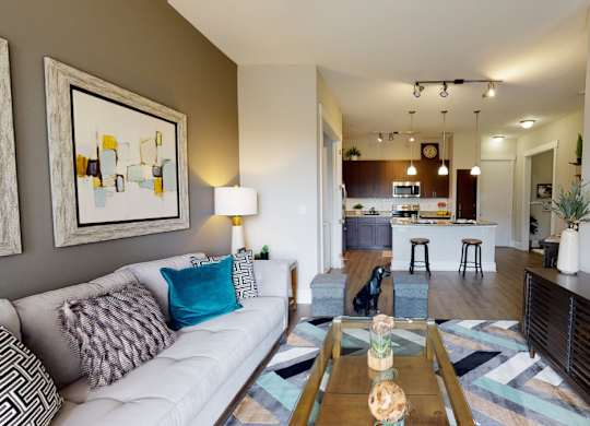A living room with a white couch and a painting on the wall.