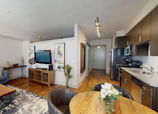 A modern living room with a grey couch, a wooden coffee table, and a flat screen TV.