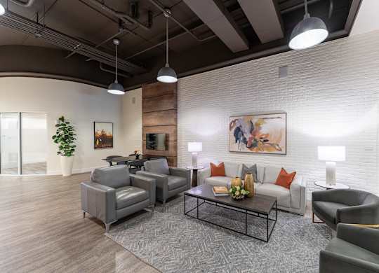 A modern living room with a grey sofa, armchairs, and a coffee table.