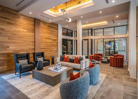 A stylish resident lobby here at Magnolia on the Green with modern seating, accent chairs, a central coffee table, warm wood wall panels, and recessed lighting, creating a welcoming, upscale gathering space.