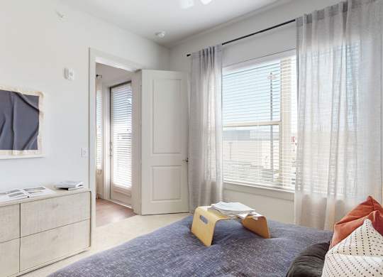 A bedroom with a bed, dresser, and window.