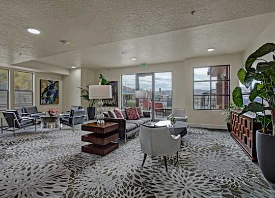 A spacious living room with a grey patterned carpet and furniture.