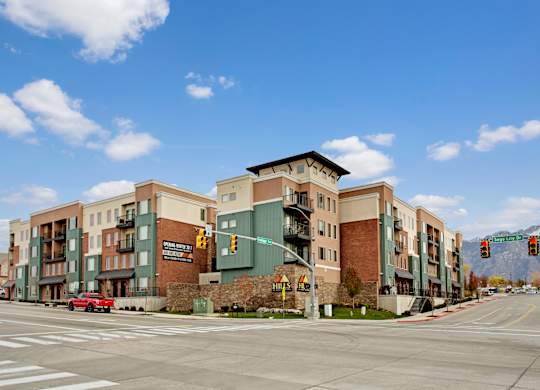 A street view of a multi-story building with a red car in front of it.