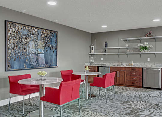 A modern dining room with a large painting on the wall and a patterned carpet.