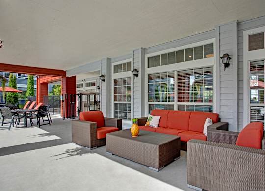 A patio with a couch, chairs, and a table with a pineapple on it.