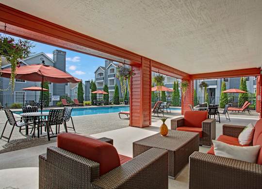A patio with red couches and a pool in the background.