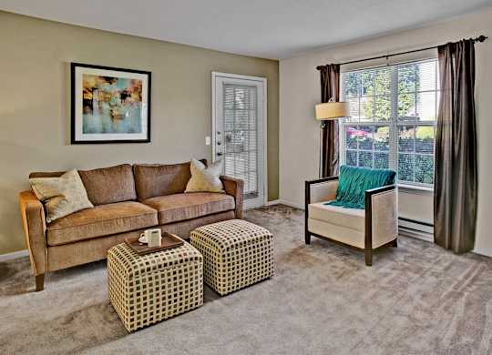 A living room with a brown couch, a green chair, and a painting on the wall.