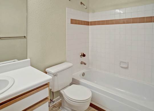 A white toilet sits next to a white bathtub in a bathroom.
