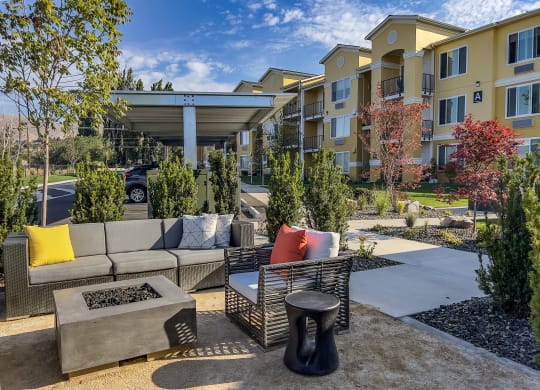 a patio with couches and a coffee table in front of an apartment building