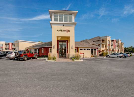 An exterior view here at Riverside 9 highlighting the welcoming leasing office entrance with tall windows, modern architecture, and convenient resident and guest parking.