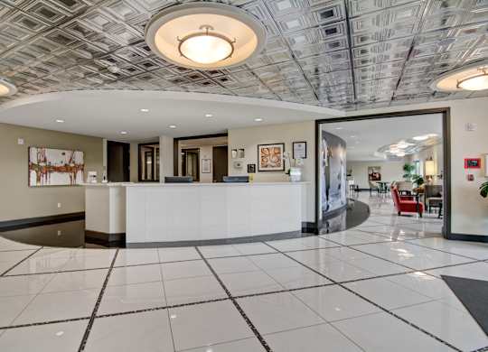 A reception area with a white reception desk and a grey and white tiled floor.