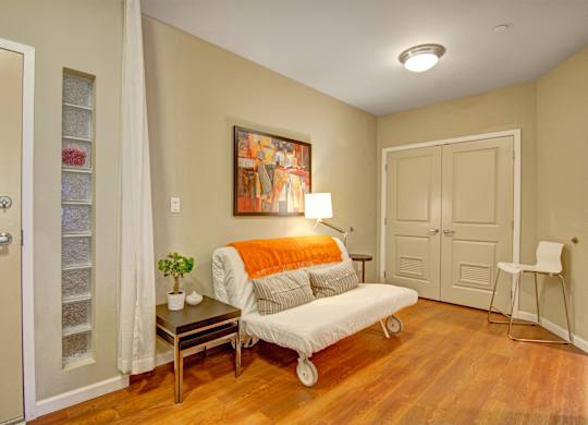A living room with a white couch and a painting on the wall.
