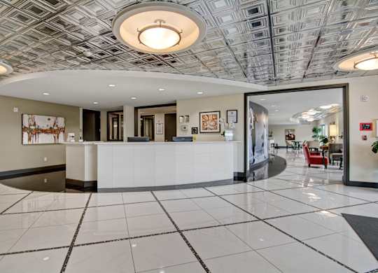 A reception area with a white reception desk and a grey and white tiled floor.