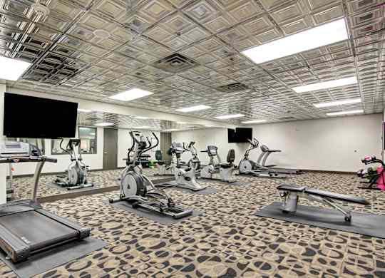 A gym with treadmills, exercise bikes and a television.