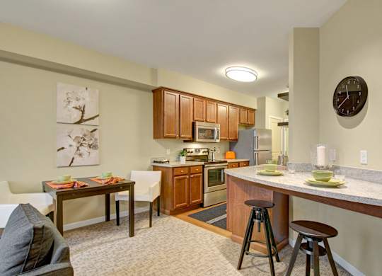 A kitchen with a table and chairs in front of it.