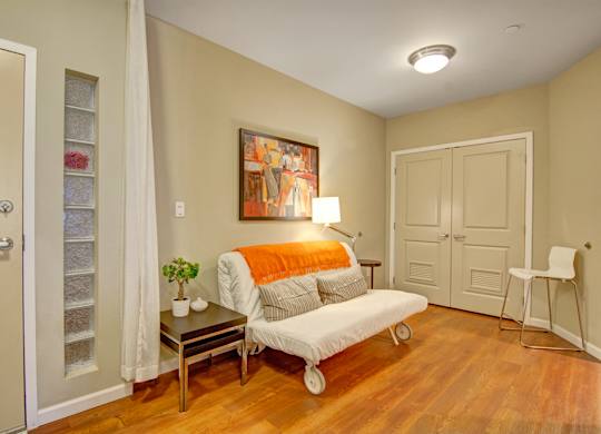 A living room with a white couch and a painting on the wall.