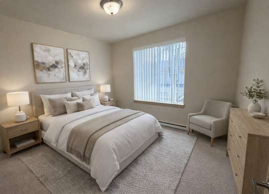 A bright bedroom here at The Vintage with soft beige carpet, light neutral walls, and a large window with vertical blinds bringing in natural light. A bed with white bedding and neutral pillows sits beside wooden nightstands with matching lamps.
