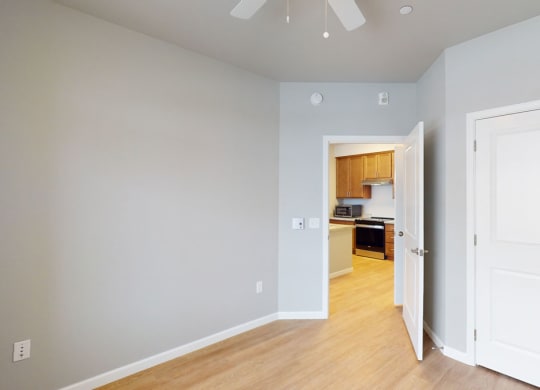a bedroom with two doors and a kitchen in the background