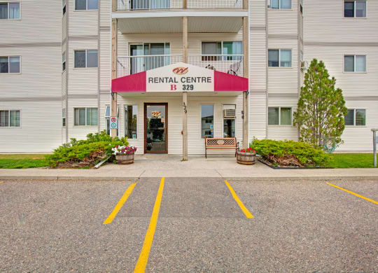 Entrance to our leasing office here at Westhaven Estates Apartment Homes with a red and white awning, surrounded by shrubs and flowers. A bench is placed under the awning, creating a welcoming feel.