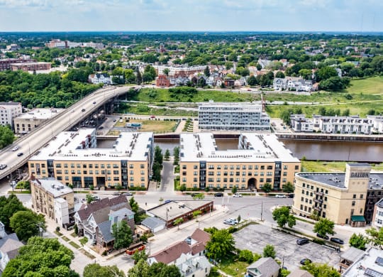 Aerial view of a cityscape featuring a large bridge over a river. Surrounding the river is River House Apartments, set amidst lush greenery.