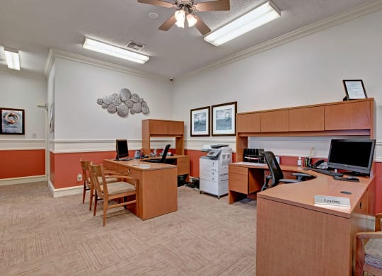 A tidy office with three wood desks, each with a computer and chairs at St. James Place Apartments.