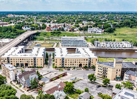A modern exterior building view of River House with large windows, a neutral-toned exterior, and a welcoming entrance. The property creates a stylish multi-story design and create an attractive, upscale atmosphere.
