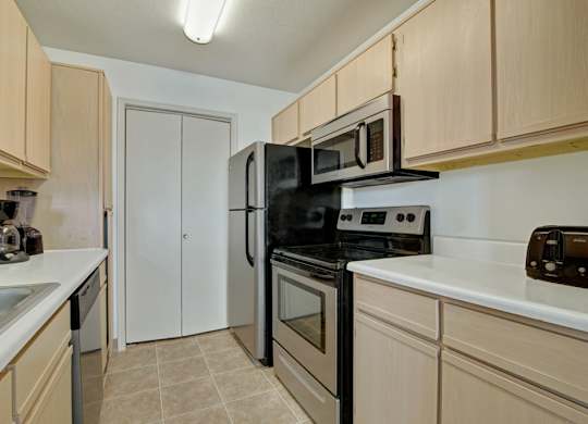 A bright kitchen here at St. James Place with light wood cabinets, white countertops, and modern appliances. A functional layout and overhead lighting create a clean and inviting atmosphere.