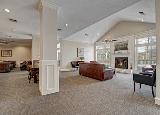 A spacious resident lounge here at St. James Place with comfortable seating, high ceilings, and large windows that bring in natural light. A cozy fireplace and open layout create a warm and inviting gathering space.