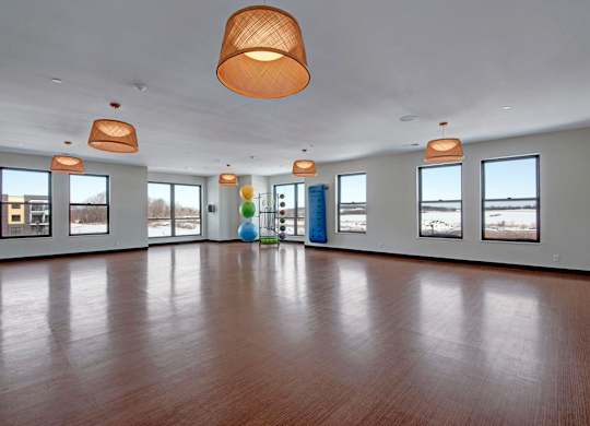 A spacious fitness studio here at The Lafayette with wood flooring, large windows, and modern lighting. A fitness equipment area and open layout create a bright, motivating space for group workouts and exercise.