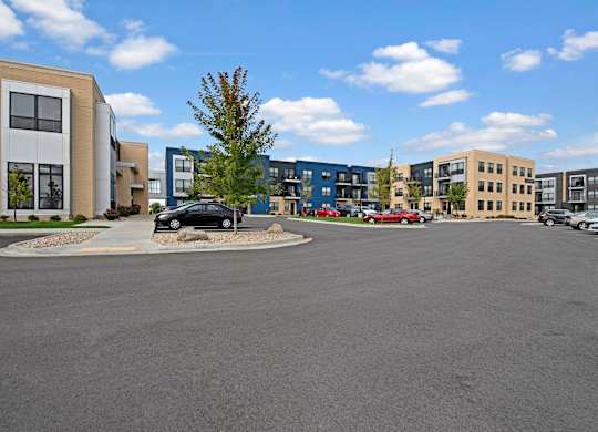 A modern exterior here at The Lafayette with contemporary buildings, private balconies, and large windows. A spacious parking area and landscaped greenery create a convenient, welcoming community environment.