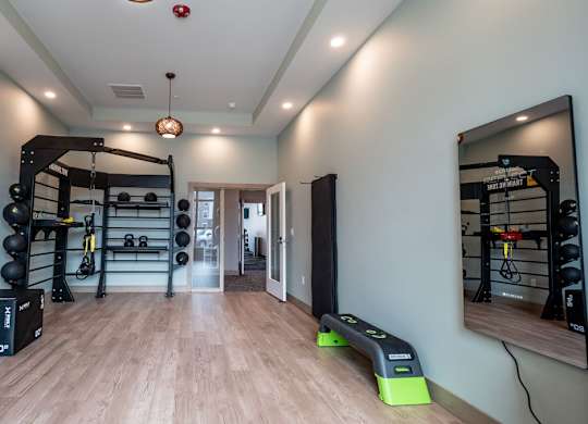 A modern fitness studio here at Van Buren East with free weights, training racks, and open workout space. Large mirrors and sleek flooring create a bright, motivating, and inviting environment.
