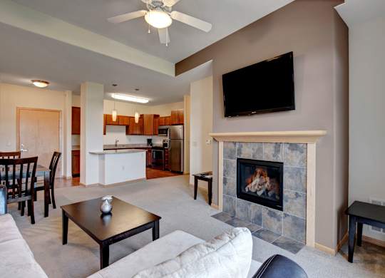 A living room here at Van Buren Place featuring a cozy fireplace with tile surround, soft neutral carpet, and an open layout that feels warm, bright, and welcoming.