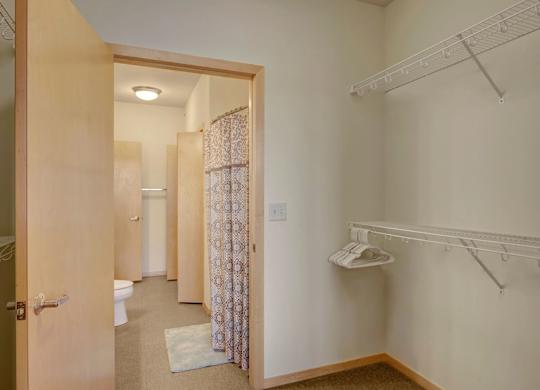 A walk-in closet here at Van Buren Place featuring open wire shelving, light wood trim, and a bright, spacious layout that feels clean and organized.