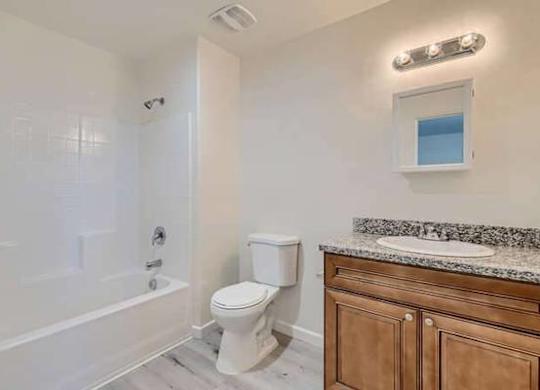 A white toilet sits next to a bathtub in a bathroom.
