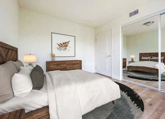 A bedroom with a large bed and a mirror on the wall.