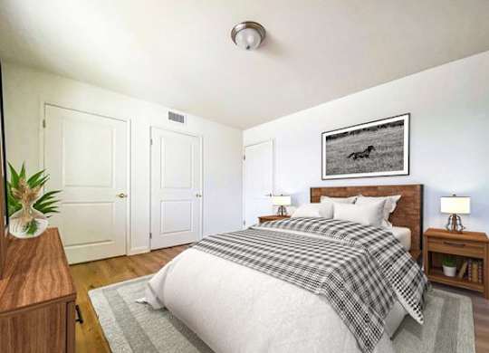A bedroom with a bed, nightstands, and a plant.