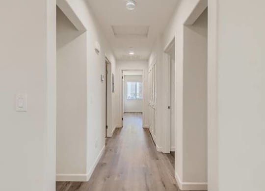 A long, narrow hallway with white walls and wood flooring.