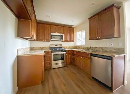 A kitchen with wooden cabinets and a stainless steel dishwasher.