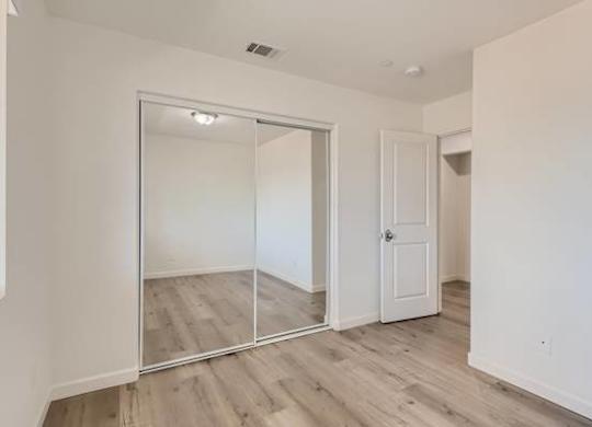 A room with a white door and a mirror on the wall.