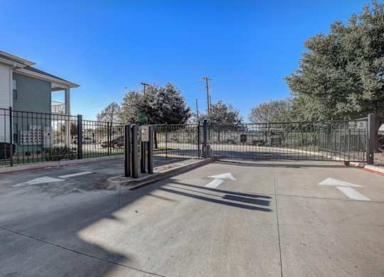 Gated community entrance drive with keypad access and wide driveway.