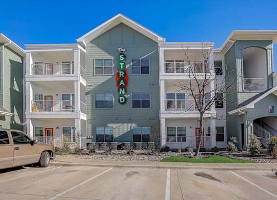 Three-story apartment building with balconies and green-and-white siding.
