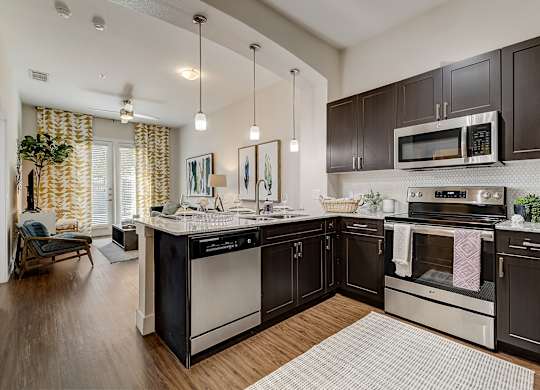 A modern kitchen with dark wood cabinets and stainless steel appliances.