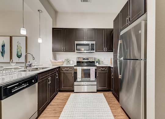 A modern kitchen with dark wood cabinets and stainless steel appliances.