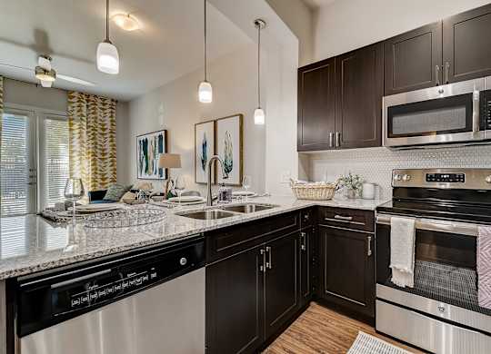A modern kitchen with dark brown cabinets and stainless steel appliances.